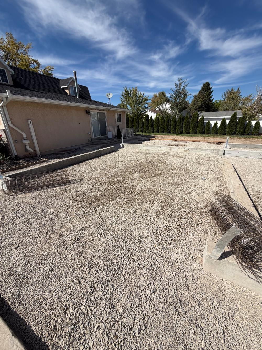 A formed and graveled building pad with utilities stubbed up, ready for concrete