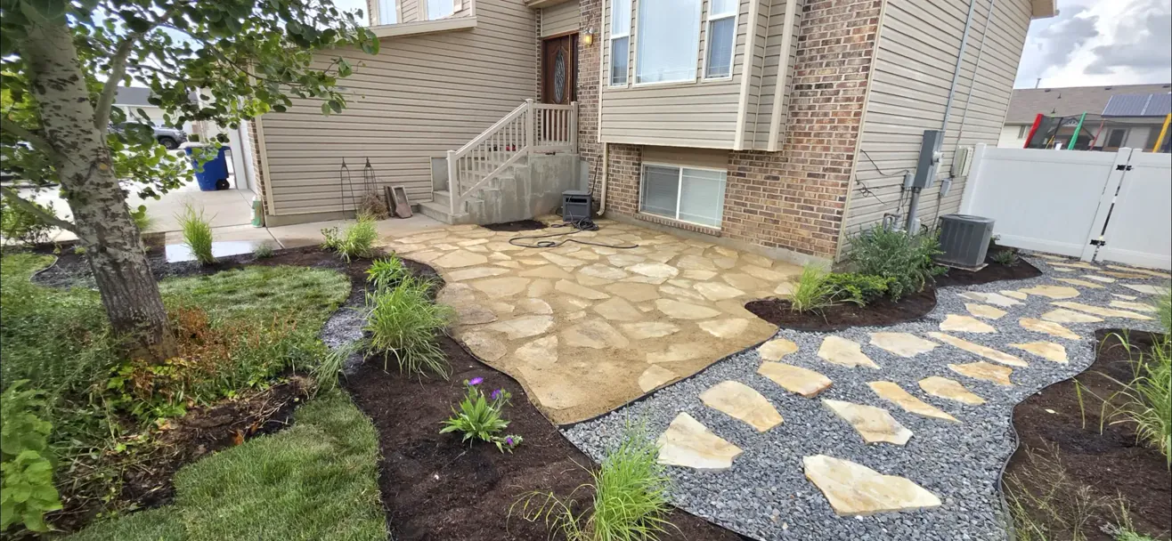 A finished flagstone patio with new planting beds and gravel edging